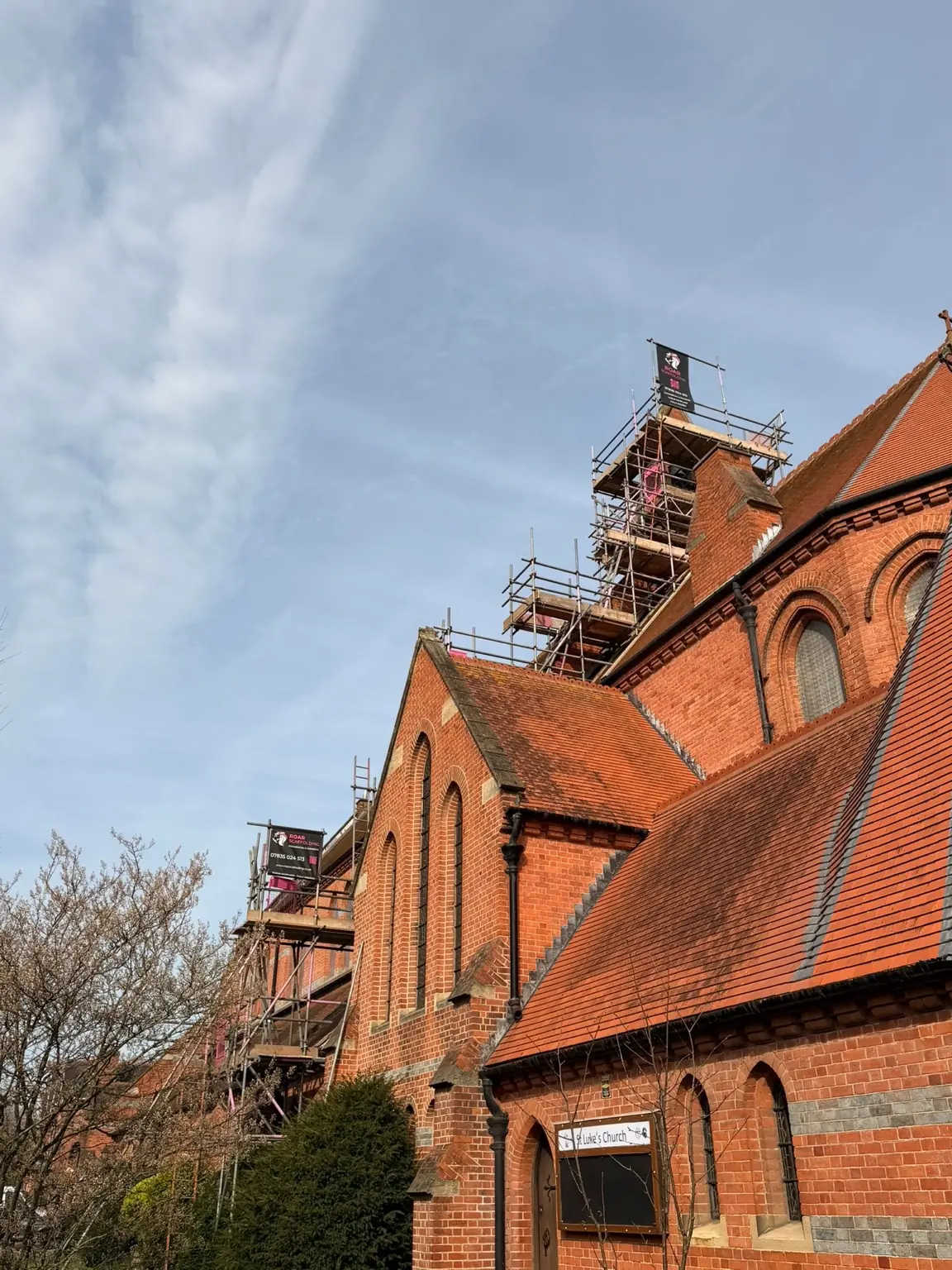 Multiple boarded scaffold lifts along the church roofline in Reading