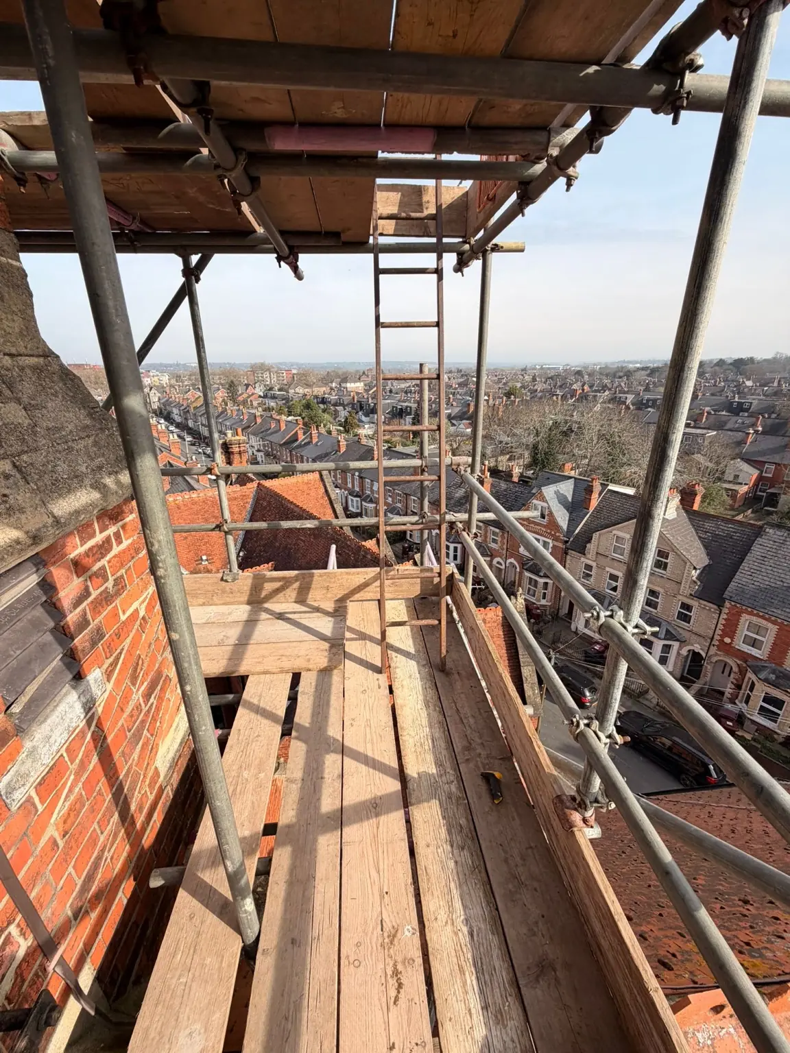 High-level boarded scaffold platform with ladder access over Reading's rooftops