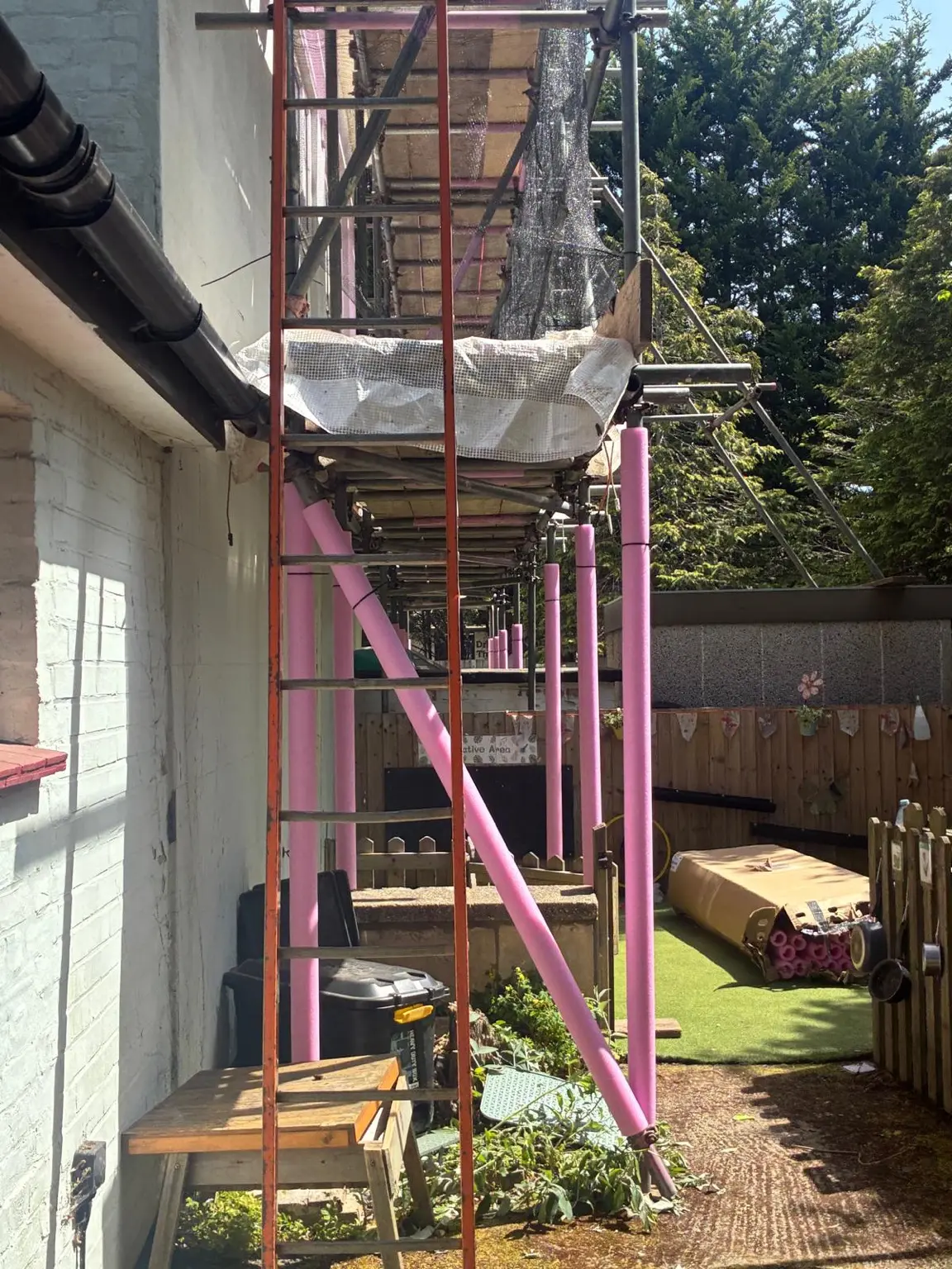 Protective pink foam fitted to scaffold standards within a nursery play area