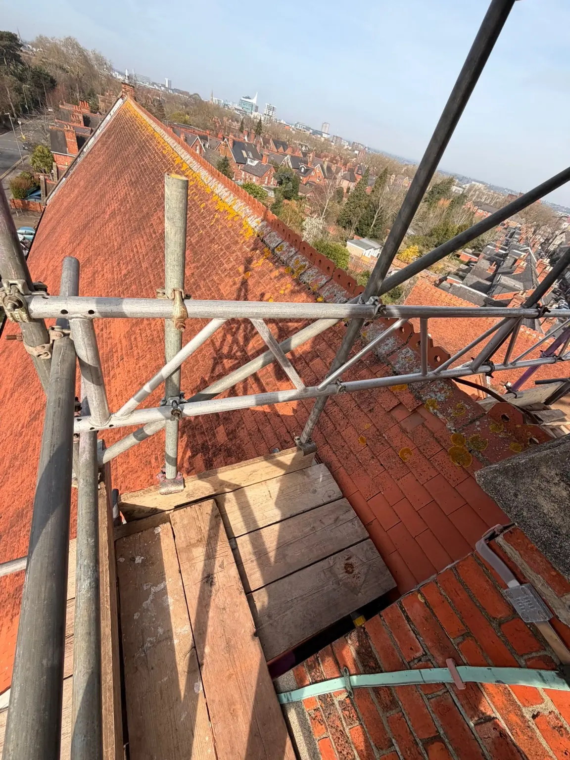 Scaffold stepped around the pitched roof of St Luke's Church with Reading's skyline behind